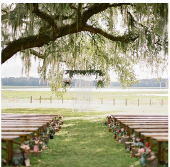 Empty lakeside ceremony lawn beneath moss-draped oak trees